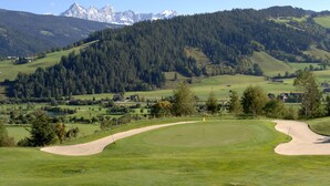 Un parcours de golf offrant une vue dégagée sur une chaîne de montagnes en arrière-plan.