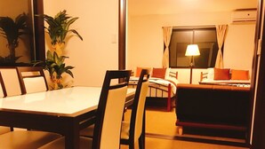 A compact hotel room with a dining table, chairs, a sofa, a bed, a lamp, and a potted plant. - GH One More Heart at Toji 3 (Kyoto)