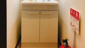 A bathroom with a white sink, a mirror, and a fire extinguisher on the wall. - GH One More Heart at Toji 3 (Kyoto)