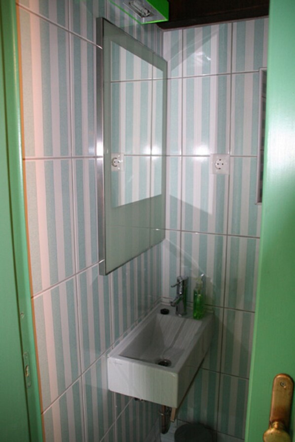 Un baño con paredes de azulejos a rayas, un lavabo y un espejo.