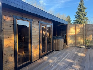 Eine Holzterrasse mit Whirlpool und überdachtem Außenbereich.