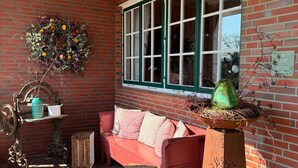 Een kamer met bakstenen muren, een rode bank, een groen raam en een decoratieve krans.