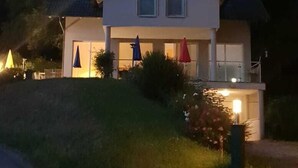 Une maison à deux étages avec un balcon, un petit jardin et une allée.