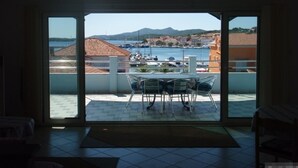 A room with a sliding glass door leading to a balcony with a table and chairs, overlooking a marina and mountains. - Apartment in Kukljica with Seaview, Terrace, Air condition, WIFI (4567-3) (Kukljica)