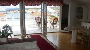 A room with a red carpet, wicker chairs, a dining table, and a view of a marina. - Apartment in Kukljica with Seaview, Terrace, Air condition, WIFI (4567-3) (Kukljica)