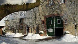 En snötäckt gata med en byggnad i tegel, som har en grön dörr och gröna fönster.