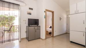 A hotel room with a TV on a cabinet, a balcony with a chair, and a large white wardrobe. - Gorgeous apartment in Povljana with WiFi (Povljana)