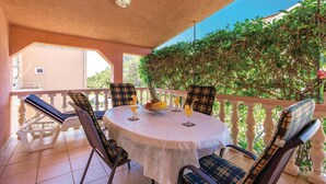 A round table with a white tablecloth, surrounded by four chairs with plaid cushions, set on a balcony with a white balustrade. - Gorgeous apartment in Povljana with WiFi (Povljana)