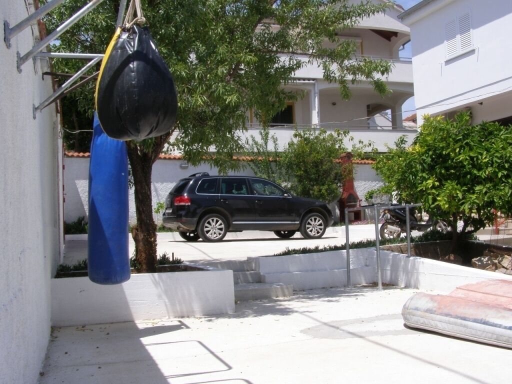 A black SUV parked in a driveway with a blue punching bag hanging on a metal frame.