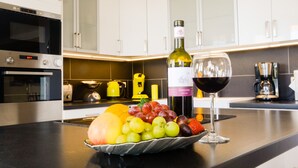 Una encimera de cocina con un frutero, una botella de vino y una copa de vino.