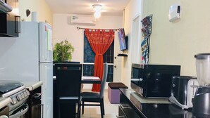 A kitchen with a refrigerator, stove, microwave, and a dining area with a chair and table. - Michelles House (Playa del Carmen)
