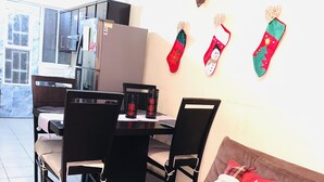 A dining area with a table and chairs, a sofa with a festive pillow, and holiday stockings on the wall. - Michelles House (Playa del Carmen)