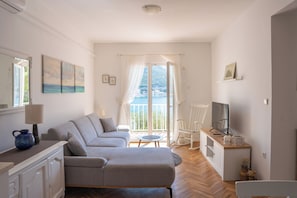 Un salon moderne avec un canapé, un téléviseur et un balcon offrant une vue agréable.
