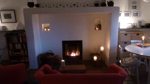 Una sala de estar acogedora con chimenea, una mesa de comedor con sillas y una estantería.
