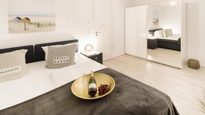 Et moderne soveværelse med seng, natbord og et stort spejl.