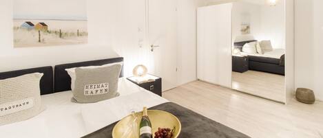 A modern bedroom with a bed, bedside table, and a large mirror.