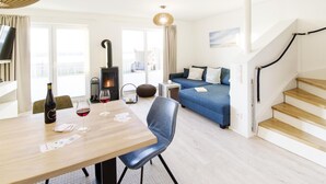 En moderne stue med et træspisebord, blå sofa og en trappe.