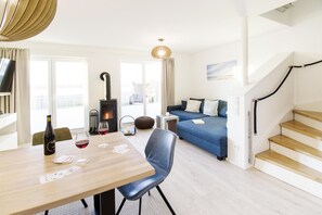 Un salon moderne avec une table à manger en bois, un canapé bleu et un escalier.