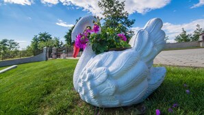Escultura de cisne branco com um vaso de flores roxas.