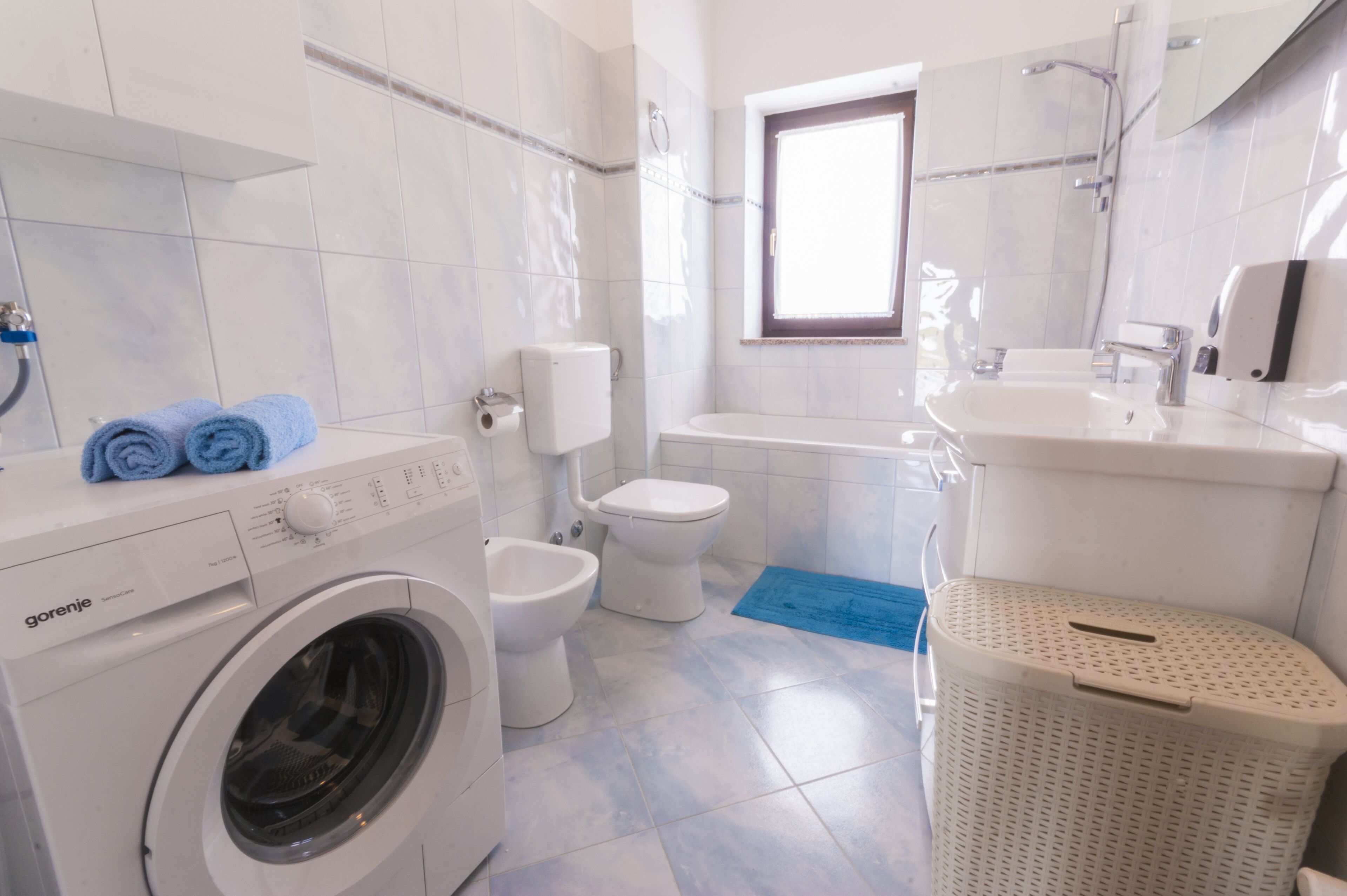 Une salle de bain équip ée d’un lave-linge, de toilettes, d’une baignoire et d’un lavabo.