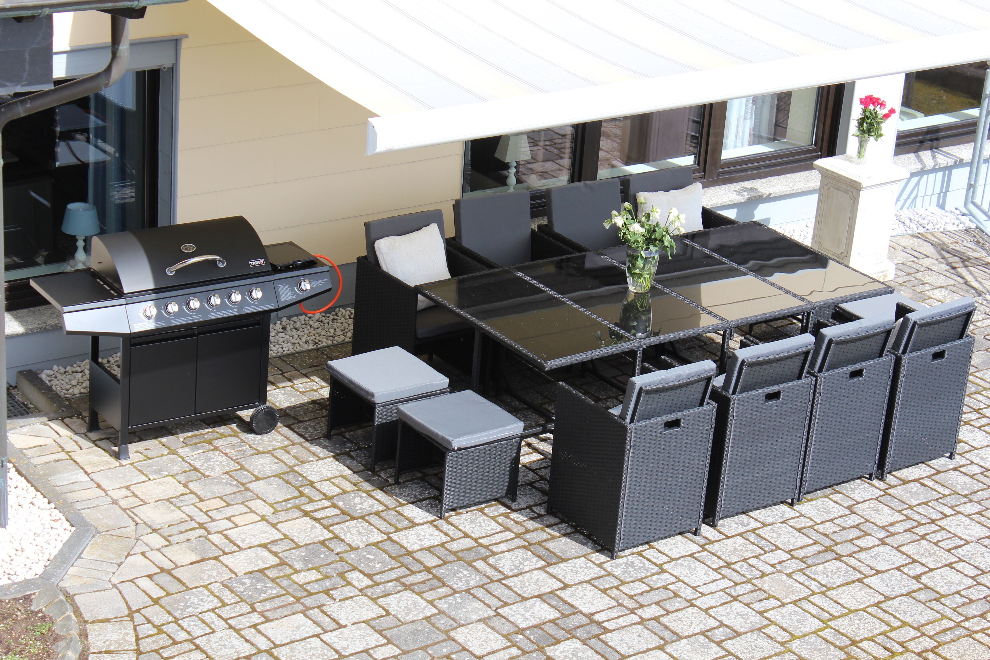 An outdoor patio with a grill, seating area, and a table with chairs.