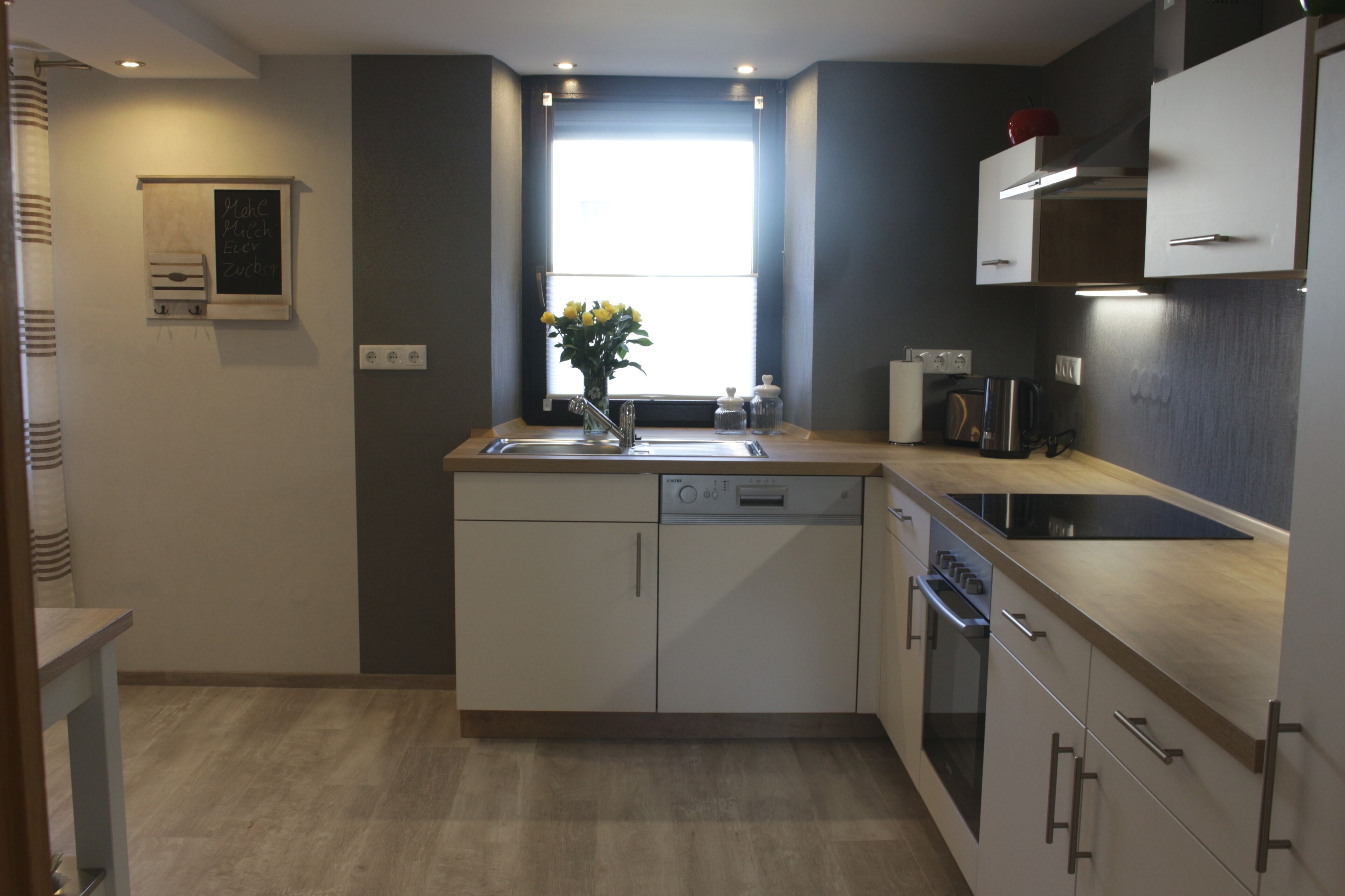 A modern kitchen with a dishwasher, oven, and a window with a view.
