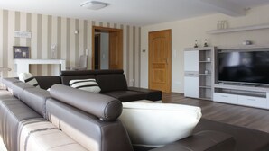 A modern living room with a sectional sofa, a flat-screen TV, and a wooden door.