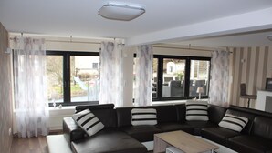 A modern living room with a sectional sofa, a coffee table, and large windows with curtains.