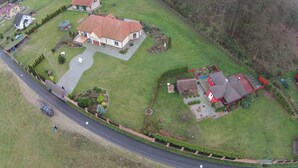 Vista aérea de una zona residencial con varias casas, una carretera y una colina arbolada.