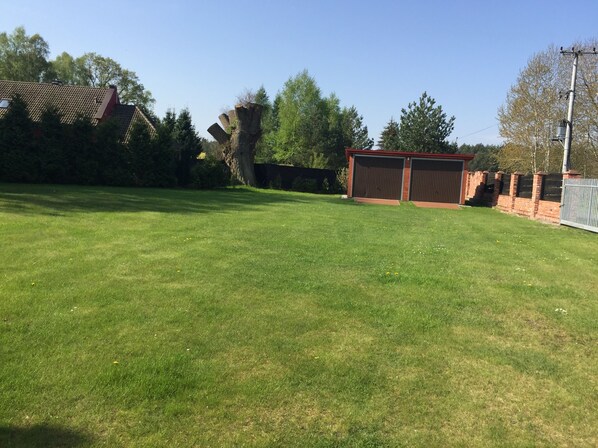 A grassy backyard with a shed and a brick wall. - Stylish house in an idyllic, quiet location, large garden. (Nowe Warpno)