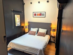 A hotel room with a bed, two bedside lamps, a framed artwork above the bed, and a window with a view. - 100% quiet in Uzès! Sw.-pool 10X5m, 70m² with AC+priv. terrace, WIFI, big garden (Uzès)