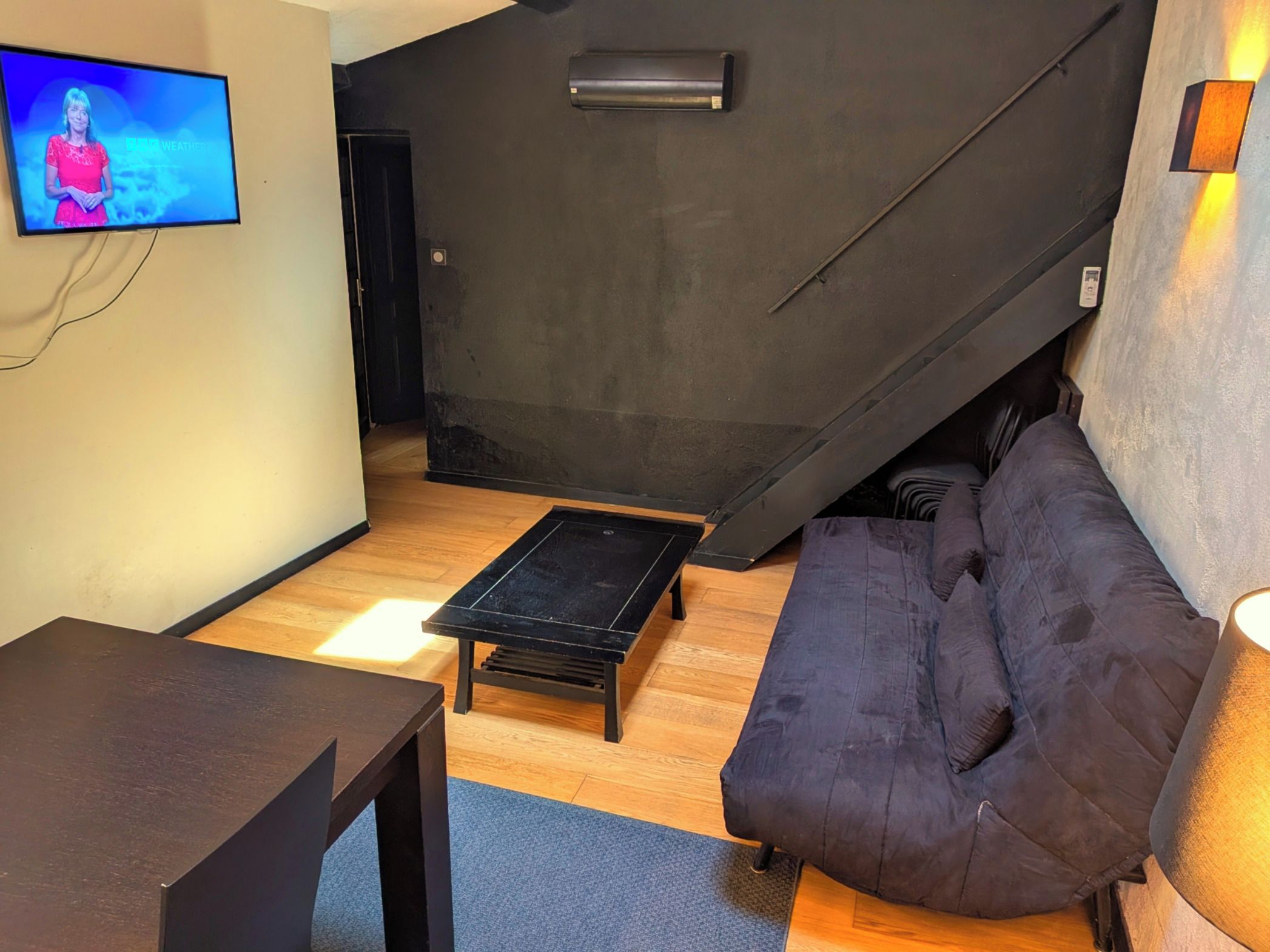 Un salon moderne avec un canapé, une table basse, un téléviseur et un escalier.