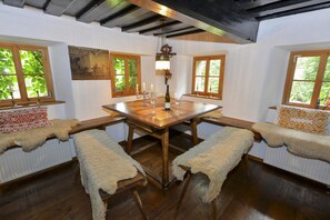 Comedor con mesa de madera, cuatro bancos y una lámpara de araña.