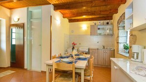 Ein Essbereich mit einem Holztisch, gedeckt für zwei Personen, eine Küche mit Holzausstattung und eine Wand mit Steinverkleidung.
