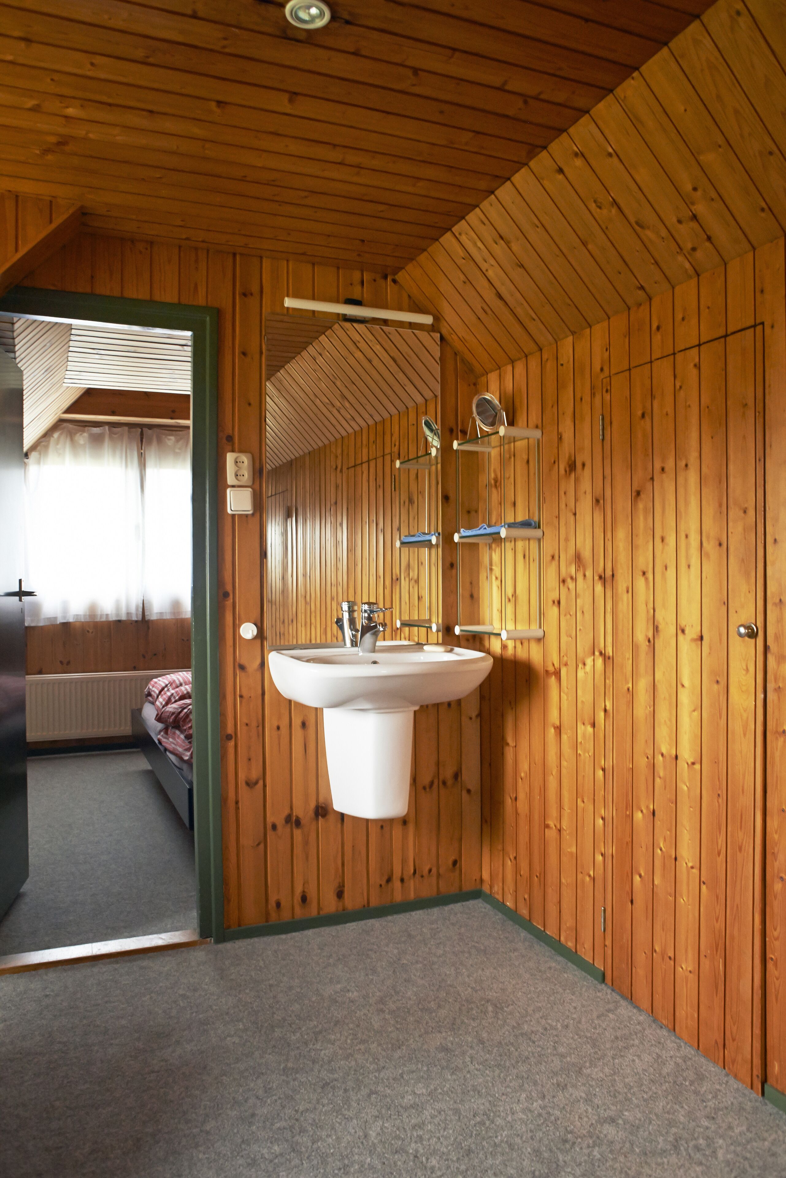 Une salle de bain avec des murs en bois, un lavabo blanc et un miroir.