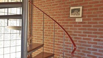 Eine Treppe mit Holzstufen und Metallgeländern in einem Raum mit Ziegelwänden und Holzboden.