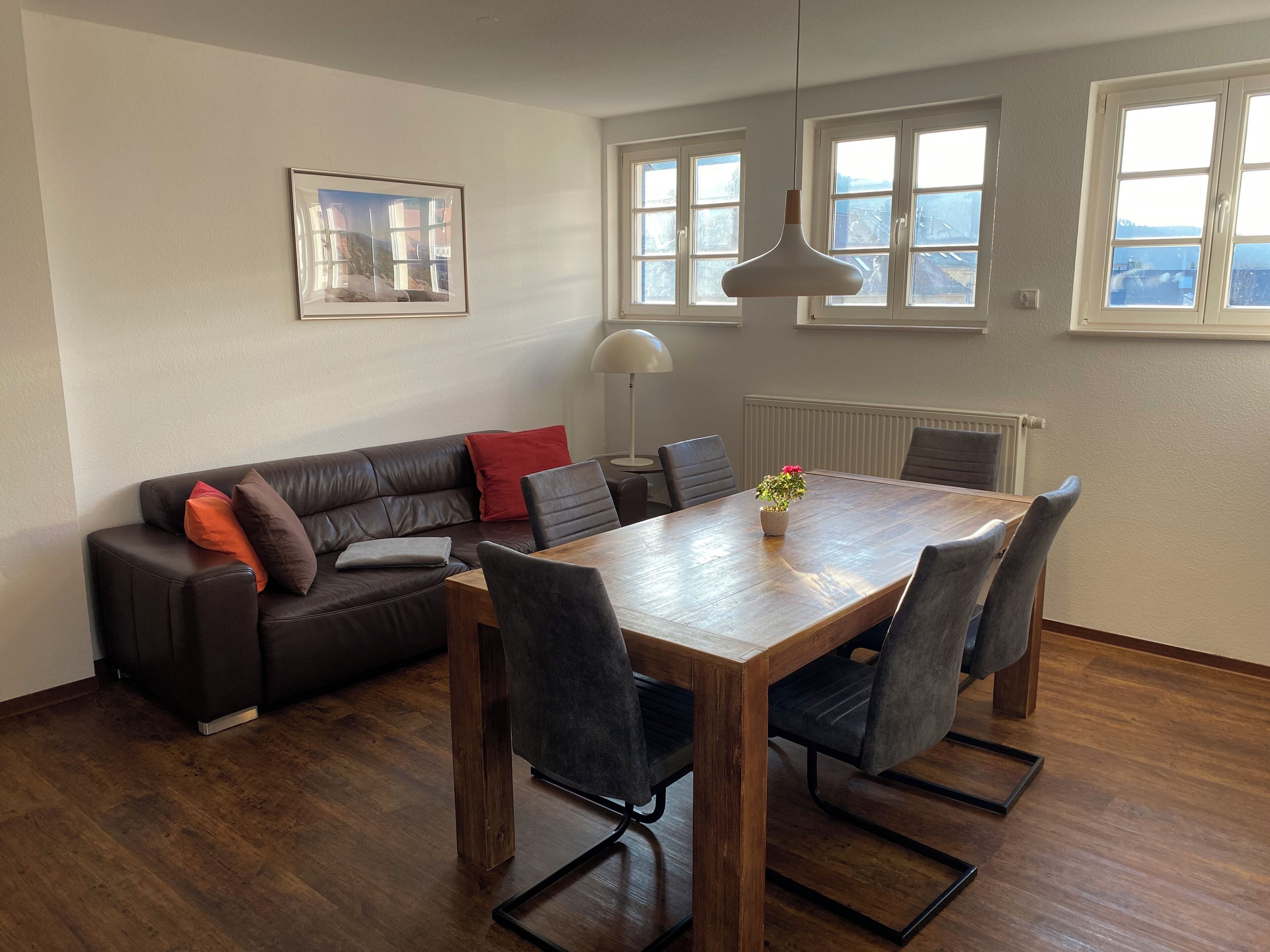Un salon moderne avec une table à manger en bois, un canapé en cuir et une plante en pot.