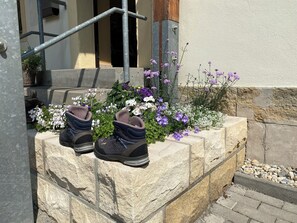 A pair of shoes on a stone ledge with a flower bed in the background.