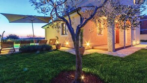 A well-lit outdoor area with a tree, a bench, and a building with a stone facade.