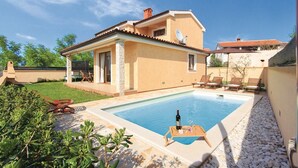 A house with a swimming pool, a patio with lounge chairs, and a satellite dish.