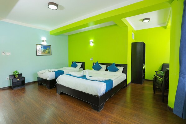 A hotel room with two beds, a desk, and a wardrobe.