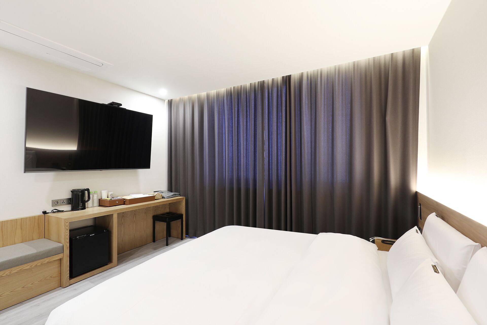 Une chambre d’hôtel avec un lit, un bureau doté d’une machine à café, une télévision et un rideau.