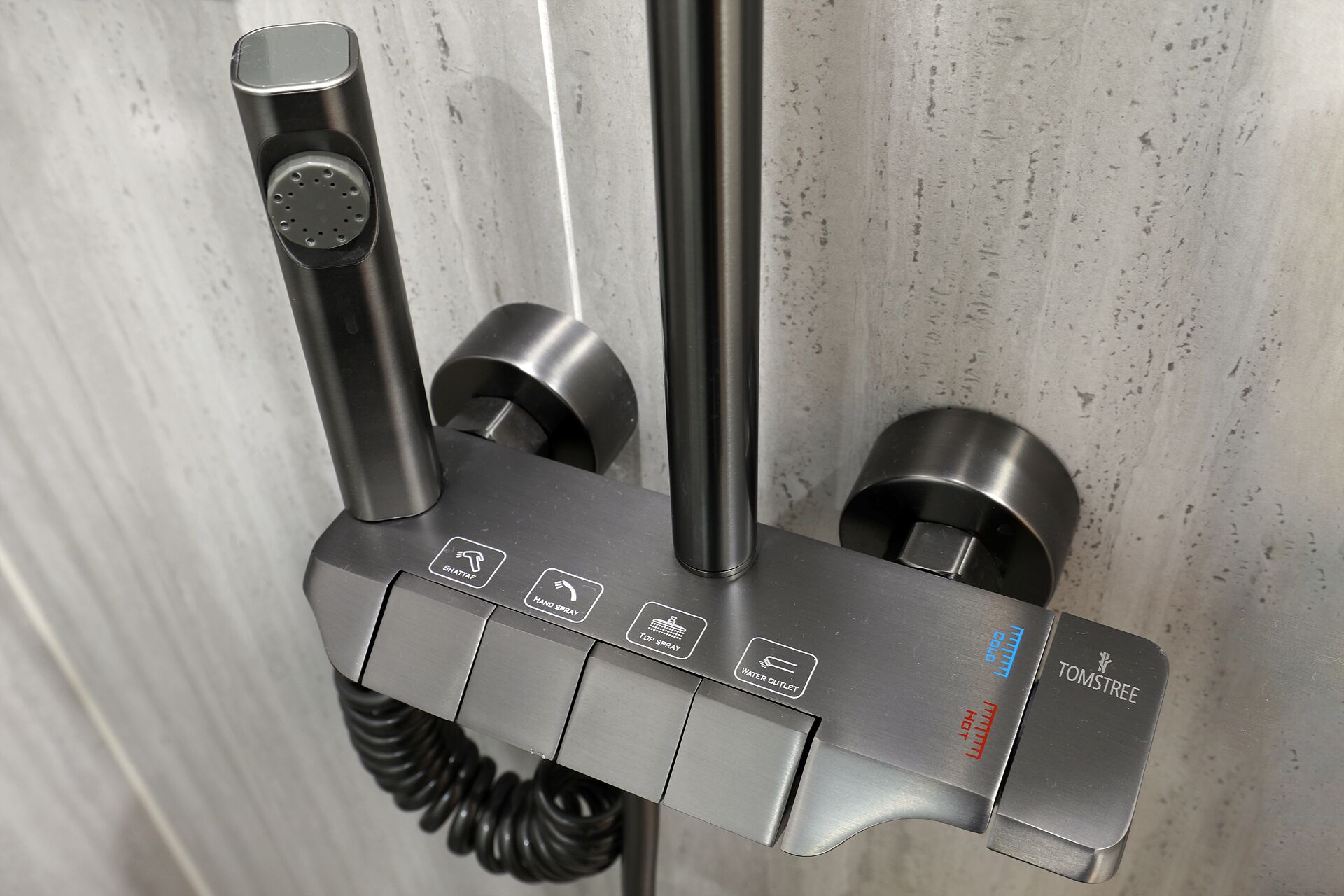 A metallic, wall-mounted device with multiple buttons and a coiled cable, likely a water fountain or similar utility.