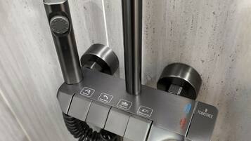 A metallic, wall-mounted device with multiple buttons and a coiled cable, likely a water fountain or similar utility.