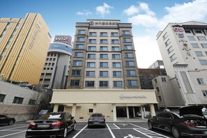 Un hotel con fachada moderna, varios pisos y un llamativo letrero que dice 'Hotel Wiz'.