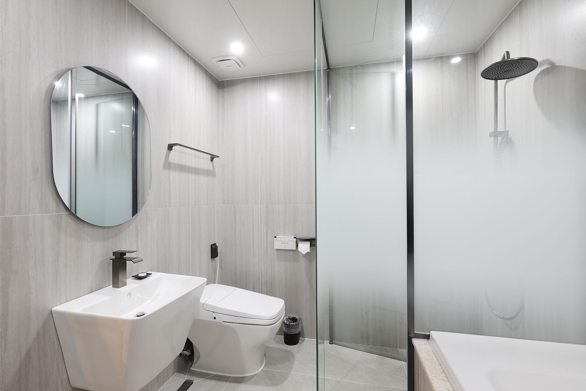 A modern bathroom with a glass shower enclosure, a toilet, and a sink.