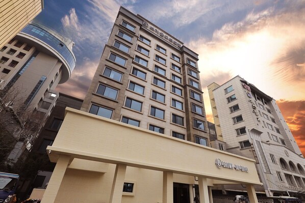 Un hotel con diseño arquitectónico moderno, que cuenta con una entrada destacada y varios ventanales.