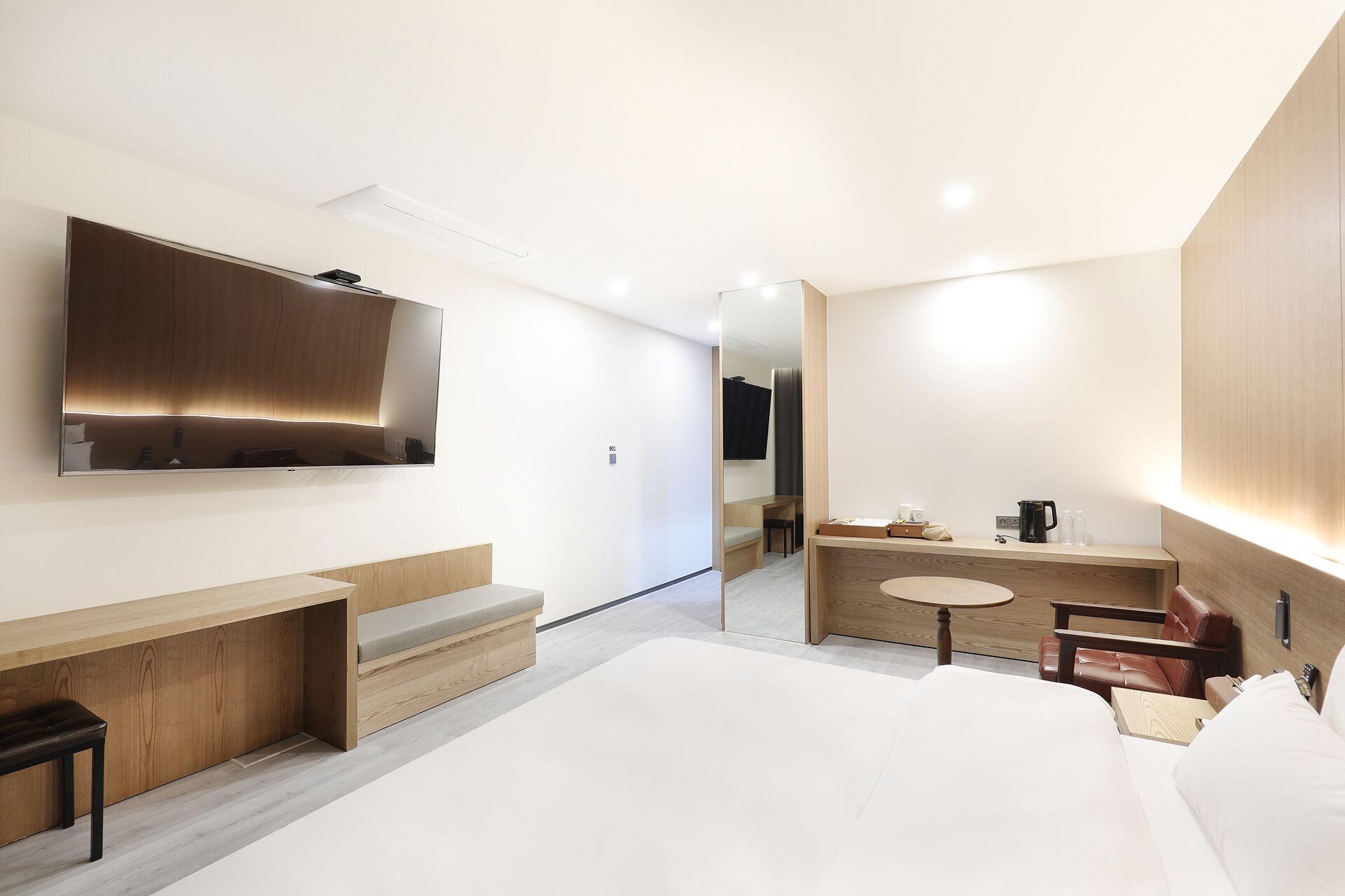 Una habitación de hotel moderna con una cama grande, un escritorio, un tocador y un televisor.