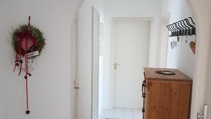 A hallway with a wooden cabinet, a rug, and a wall-mounted decoration. - Cozy city apartment with carport for 2 to 5 people near the thermal baths (Bad Reichenhall)