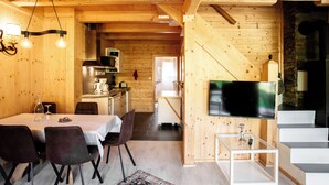 A wooden interior with a dining area, kitchen, and a TV mounted on the wall.